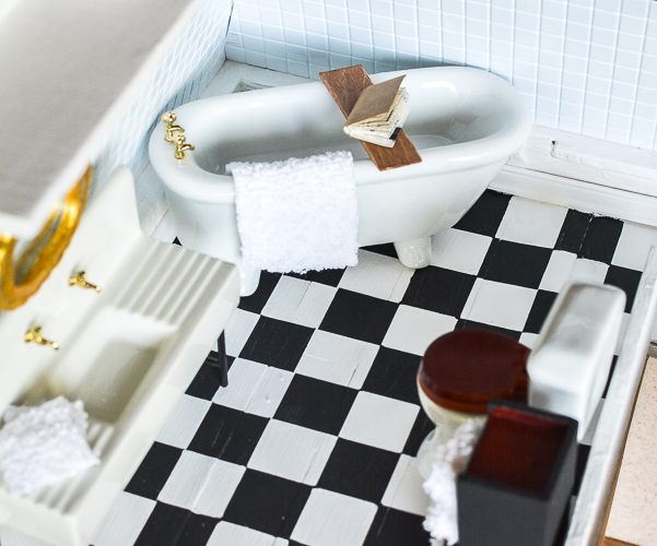 Dollhouse master bathroom decor ideas for a farmhouse bathroom. This tiny bathroom has it all, a claw tub, farmhouse sink, black and white checkered floor and cute DIY wall art.