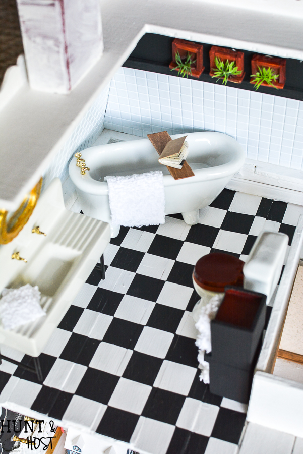 Dollhouse master bathroom decor ideas for a farmhouse bathroom. This tiny bathroom has it all, a claw tub, farmhouse sink, black and white checkered floor and cute DIY wall art.