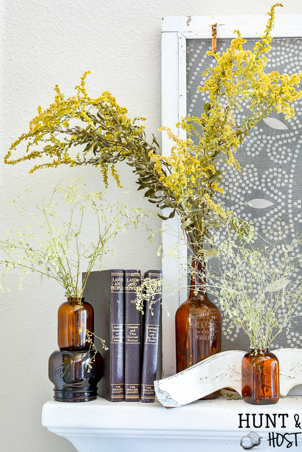 Decorating the mantel for fall with amber glass jars and roadside dreid flowers.