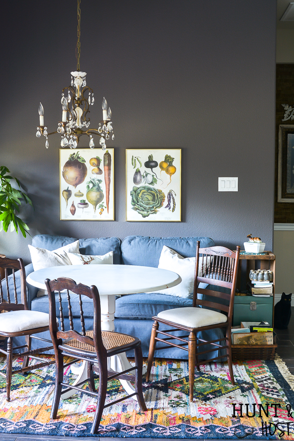 This moody boho vintage breakfast room takes advantage of the vibrant color palette popular in 2019 with a vintage chandelier, dark IKEAS sofa, vintage farmhouse prints and tons of texture you are sure to see some boho decorating ideas you can steal. #bohodecor #vintagestyle #breakfastroomdecor #moodycolors #coloroftheyear #painttrends2019 #vintagechandelier