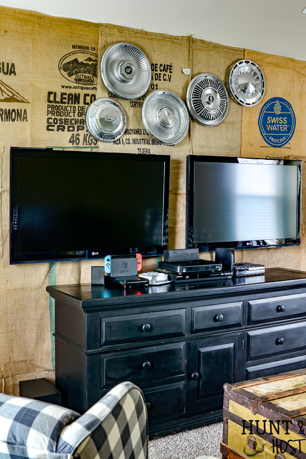 What a great game room idea! This rustic cabin lodge game room has great decorating ideas. a tutorial on how to hang a wall mounted TV (or two for a Fortnight lover's paradise!) plus an inexpensive DIY burlap wall covered in coffee bean sacks. All the elements for the perfect family game room with a cozy cabin style! #SANUS #SANUSspaces @SANUS @SANUSsystems #gameroomideas #burlapwalls #DIYwallpaper #mediaroom #TVmount #rusticroom #familyroomideas #rusticdecorideas
