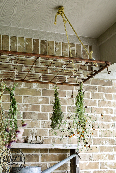 The perfect plant drying rack for your patio. If you want a French country feel on your porch then a vintage baby mattress spring is the best idea! Maybe you can even use it for a herb drying rack if you are a foodie! #herbdryingrack #diydryingrack #wildflowers #herbdrying #cozyporch #porchquilt