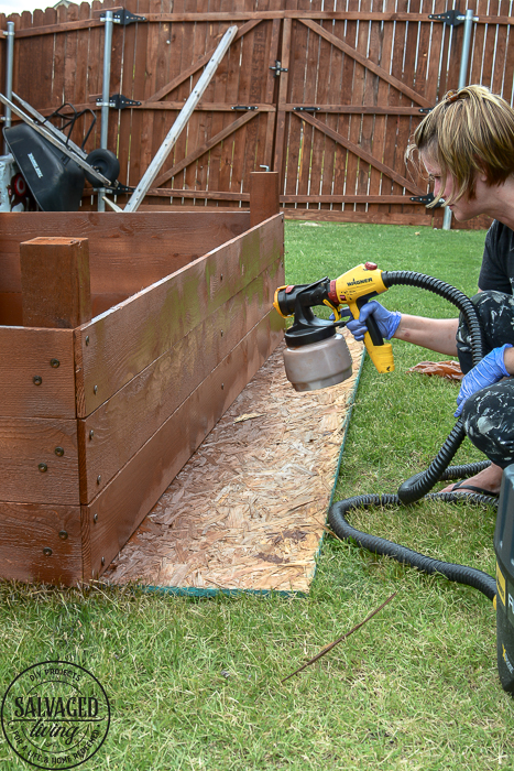 Learn how to spray stain on wood along with tips on how to clean your sprayer when you spray an oil based stain. HINT: it is so much easier than you think! This DIY raised garden bed got a spray stain that will help the wood look good and last longer and it only took minutes to do,. #wagnerspraytech #spraystain #oilbasedstain #paintcleanup #sprayertips #stainedwood #flowergarden #vegetablegarden #raisedbed #landscapedecor #fencestain #diyfencestain