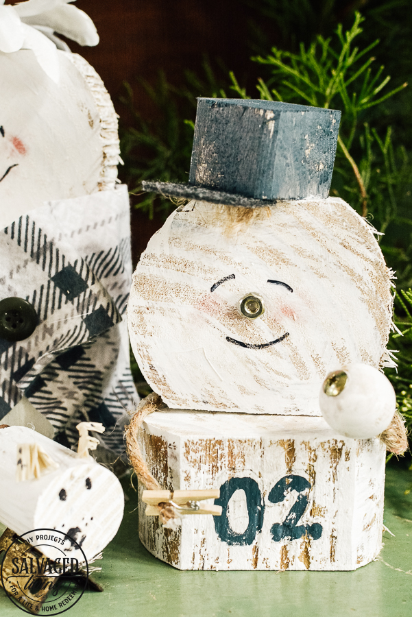 Learn how to make a cheap and easy DIY scrap wood snowmen family. The perfect Christmas decoration or gift idea for a family. This easy snowman craft lets you personalize each snowman face and outfit with junk art from your house! #holidaydecor #handandeChristmas ##snowmancrafts #woodensnowmen #farmhouseChristmas