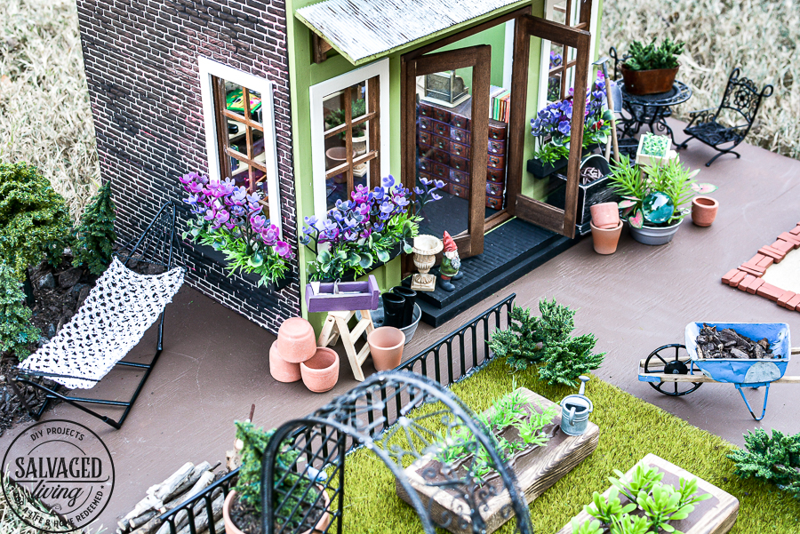 Tour a miniature vintage garden shop dollhouse for great ideas for your own dollhouse decor. See how to make a cozy home, lush garden and outdoor miniature yard! COmplete with garden gnomes, miniature potted plants and sitting areas. #dollhouse #miniatures #DIYdollhouse #vintagegarden #tinydecor