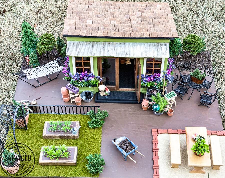 Tour a miniature vintage garden shop dollhouse for great ideas for your own dollhouse decor. See how to make a cozy home, lush garden and outdoor miniature yard! COmplete with garden gnomes, miniature potted plants and sitting areas. #dollhouse #miniatures #DIYdollhouse #vintagegarden #tinydecor