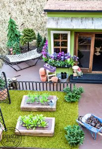 Tour a miniature vintage garden shop dollhouse for great ideas for your own dollhouse decor. See how to make a cozy home, lush garden and outdoor miniature yard! COmplete with garden gnomes, miniature potted plants and sitting areas. #dollhouse #miniatures #DIYdollhouse #vintagegarden #tinydecor