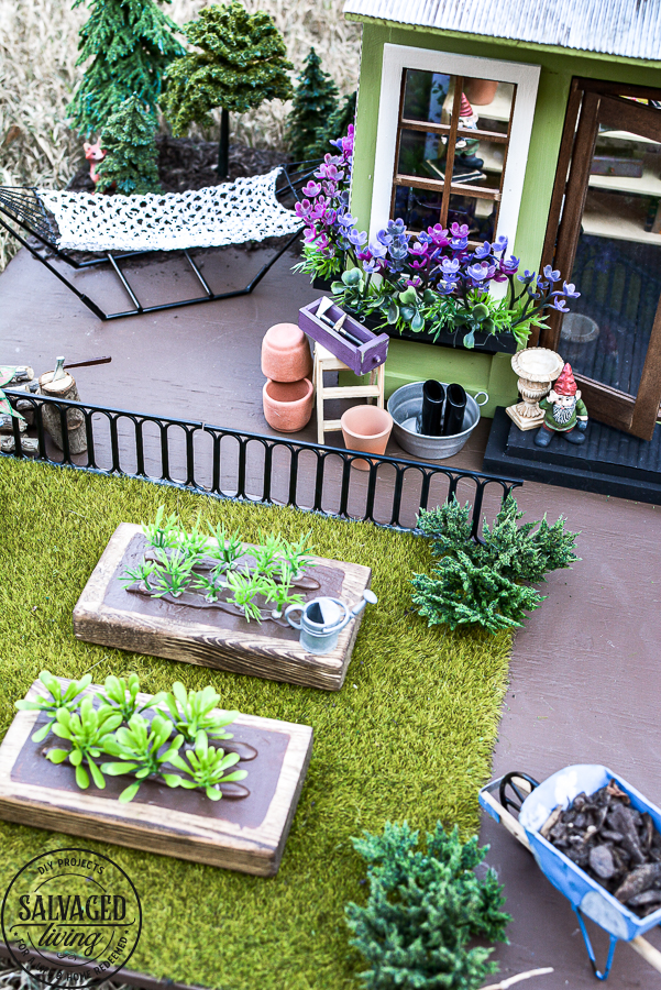 Tour a miniature vintage garden shop dollhouse for great ideas for your own dollhouse decor. See how to make a cozy home, lush garden and outdoor miniature yard! COmplete with garden gnomes, miniature potted plants and sitting areas. #dollhouse #miniatures #DIYdollhouse #vintagegarden #tinydecor