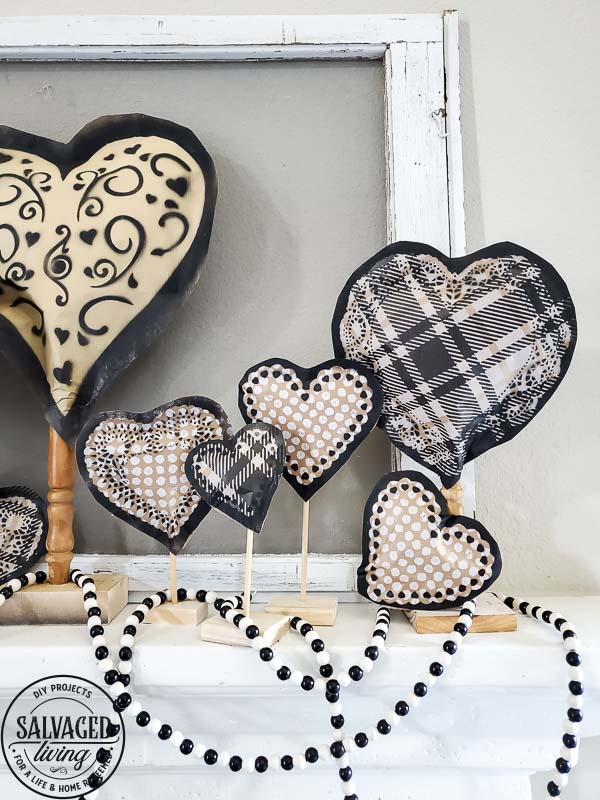 Learn how to make gorgeous giant paper hearts for Valentine's Day decorating on repurposed spindle stands. This dollar store craft is perfect for a farmhouse Valentine theme. #vintageValentine #upcycledprojectidea #spindle #papercraft #stencilart #valentinesdaymantel