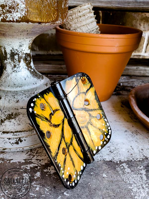 Wonder what to do with old door hinges? Try this upcycled door hinge butterfly project for a fun and beautiful addition to your spring decor ideas. These painted butterflies are perfect for your patio and potted plants. Truly adorable yard art you can DIY with thrifted or left over materials! #butterflyart #doorhinge #upcycledcraft #springdecor #springcraft