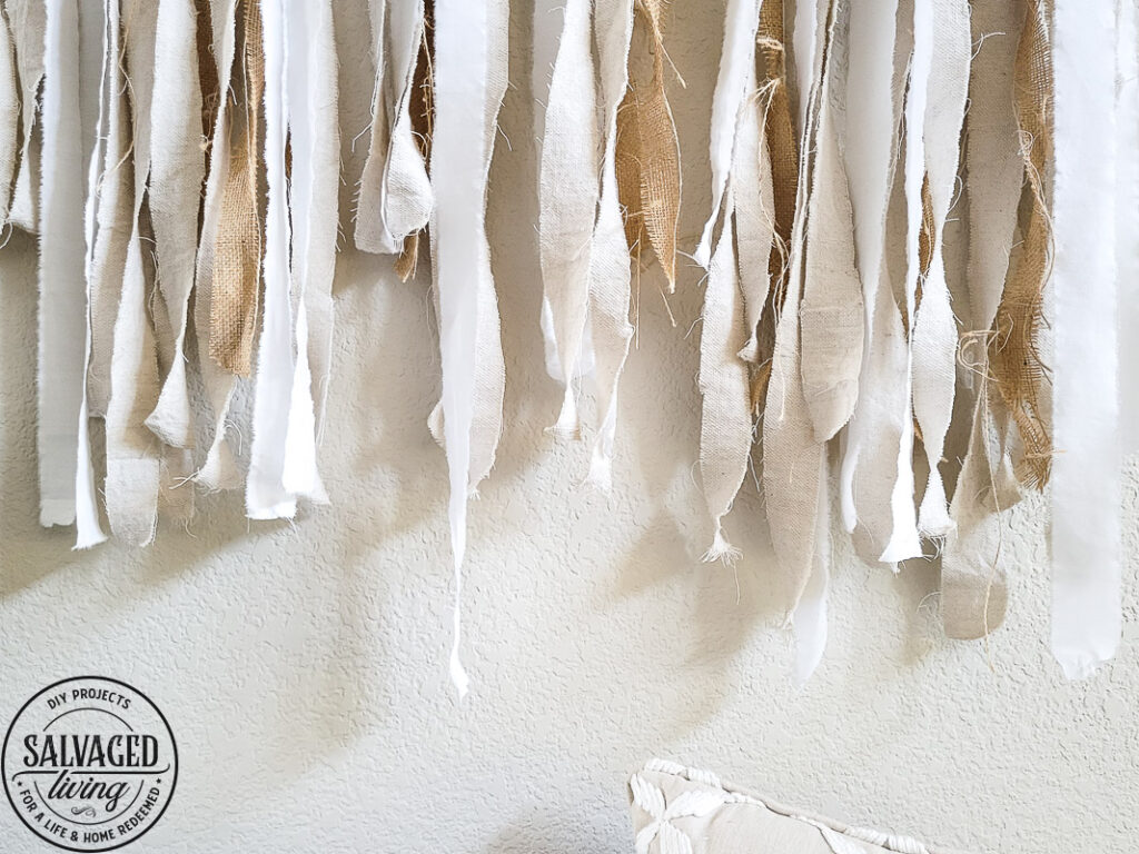 Learn how to make the large scale wall hanging I use in my living room. This shabby chic wall art is perfect fora large space or make it small and DIY this idea to fit your needs. Using an old sheet, burlap and drop cloth you can create a boho wall hanging in no time. #dropclothcraft #walldecor #wallartideas #DIYbohodecor