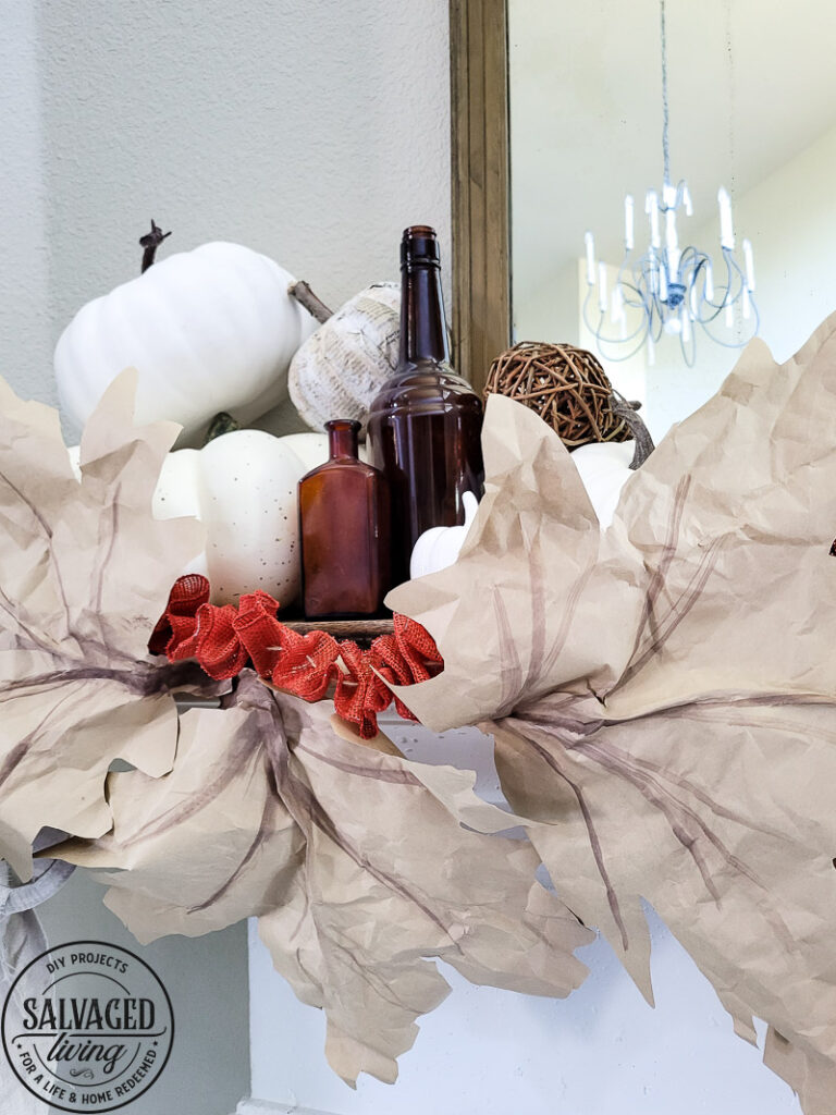 Learn how to make DIY giant paper leaf garland for your fall mantel or fall decorating. This budget garland idea is perfect to add a warm touch of fall to your home and the tutorial is so easy! Mix in some white pumpkin decor, gathered ribbon garland and cozy books for a cozy fall decor idea! #fallvibe #papergarland #papercraft 