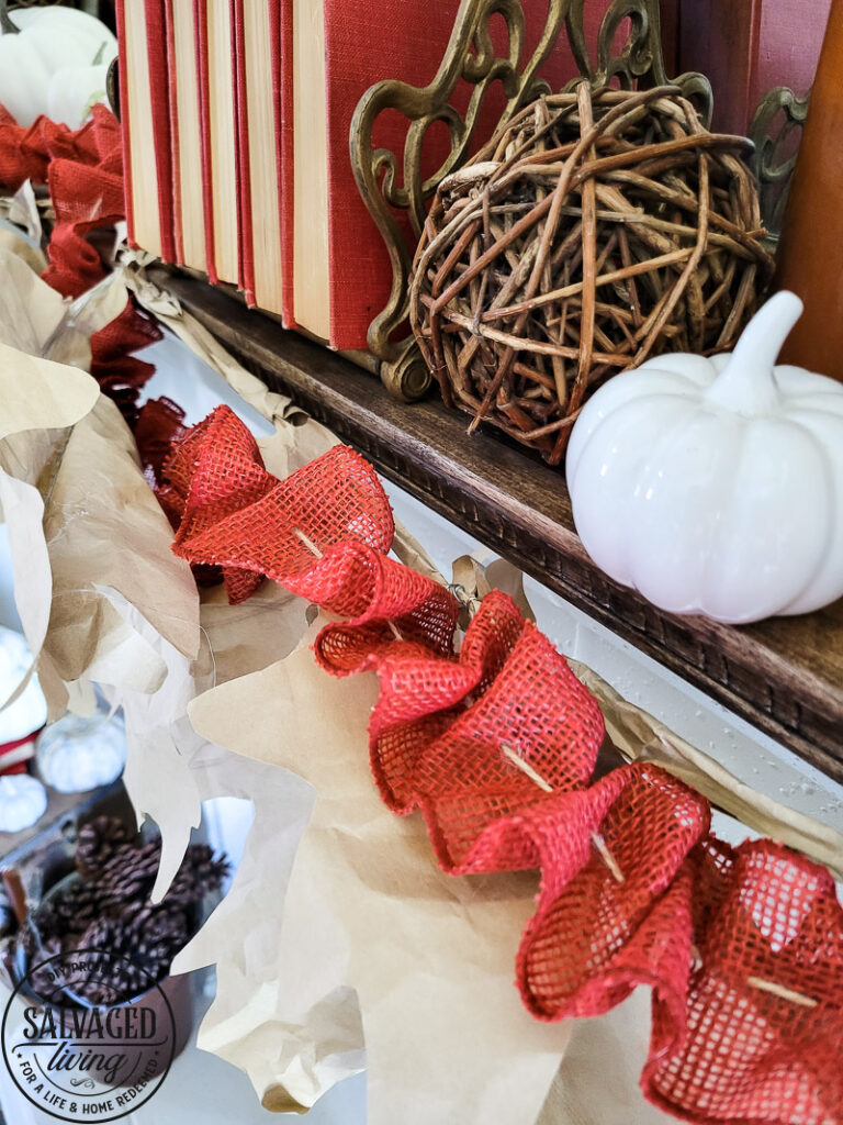 Learn how to make DIY giant paper leaf garland for your fall mantel or fall decorating. This budget garland idea is perfect to add a warm touch of fall to your home and the tutorial is so easy! Mix in some white pumpkin decor, gathered ribbon garland and cozy books for a cozy fall decor idea! #fallvibe #papergarland #papercraft 