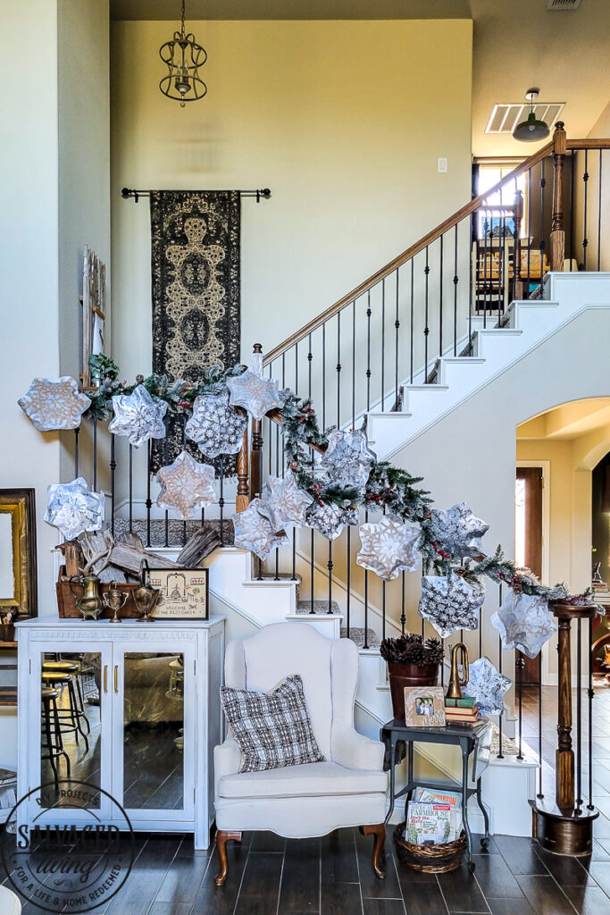 This simple DIY snowflake garland from dollar store felt pieces and Rust-Oleum Imagine spray paint is the perfect winter wonderland addition. Bring a flurry of snow to your holiday home decor with a papercraft for any decor style. The perfect DIY staircase decorating idea for your holiday banister! #rustoleum #rustoleumimagine #snowflake #winterwonderland #holidaydecor #holidaydecorating #christmasdecor #sponsored #staircasedecor 