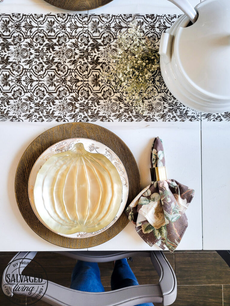 Thrifted finds and dollar store items come together for a beautiful fall table that looks expensive but isn't! I love a good mix of old and new, thrifted and found for a cozy fall table that I can be proud of. If you wonder how to set the table for Thanksgiving this is a great DIY table runner idea for you! #falltablescape #thanksgivingtable #stencilpidea #DIYtablecloth