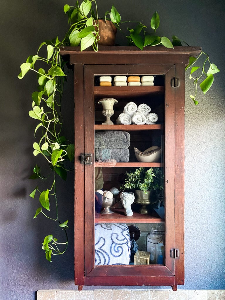 a thrifted cabinet found at a garages sale is perfect for a cozy bathroom upgrade, come see how I decorated this garage sale cabinet for function and style. #bathroomdecor #vintagebathroomstyle #cozybathroom