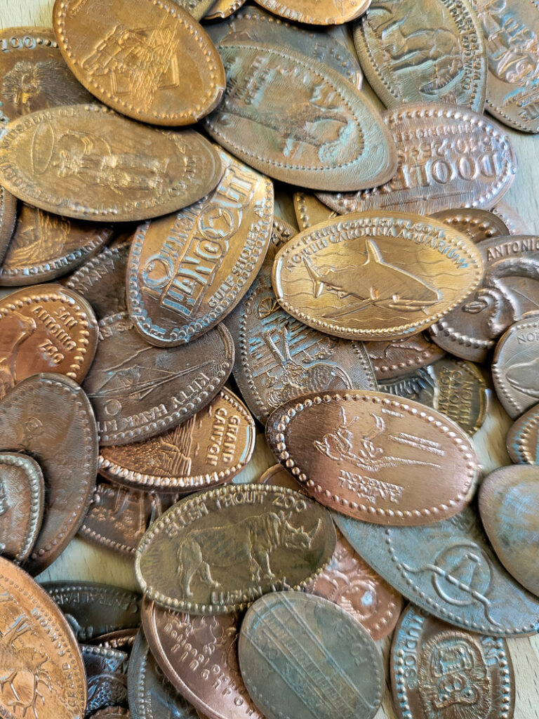 How to make a pressed penny bracelet. This DIY charm bracelet is made from inexpensive collectible souvenirs. Find the best vacation memory in these pressed penny pieces! Then take them home amd add them to your memory keeping charm bracelet, copper is so beautiful and perfect for reliving favorite vacation spots all while looking uniquely stylish! This is an easy DIY jewelry project that has a ton of meaning. #charmbraceletDIY #pressedpennyidea #pennydisplay