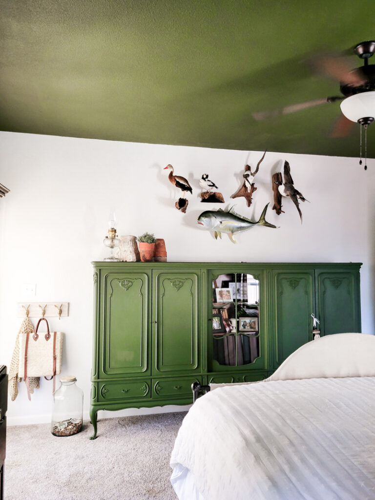 Master bedroom redo. Vintage paint color palette and budget curtain hack, get the look for less from Ballard Design. Buffalo check curtains make big impact for cheap. #greenbedroom #vintagebedroom #taxidermy #affordablecurtains
