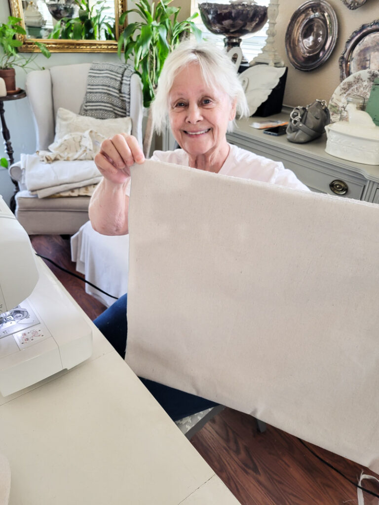 how to make DIY no-sew curtains for a farmhouse feel. This easy no sew curtain idea is perfect for decorating beginners and budget decorating enthusiasts! Drop cloth curtains are cheap and the perfect neutral curtain to accent a room. You can sew up this curtain tutorial but a little fabric glue will do the trick. If you are looking for the perfect white curtains or neutral curtain decor, this is the window valance idea for you! #DIYcurtain #budgetcurtain #nowsewwindowtreatment #nosewcurtain