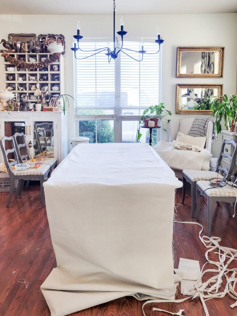 how to make DIY no-sew curtains for a farmhouse feel. This easy no sew curtain idea is perfect for decorating beginners and budget decorating enthusiasts! Drop cloth curtains are cheap and the perfect neutral curtain to accent a room. You can sew up this curtain tutorial but a little fabric glue will do the trick. If you are looking for the perfect white curtains or neutral curtain decor, this is the window valance idea for you! #DIYcurtain #budgetcurtain #nowsewwindowtreatment #nosewcurtain