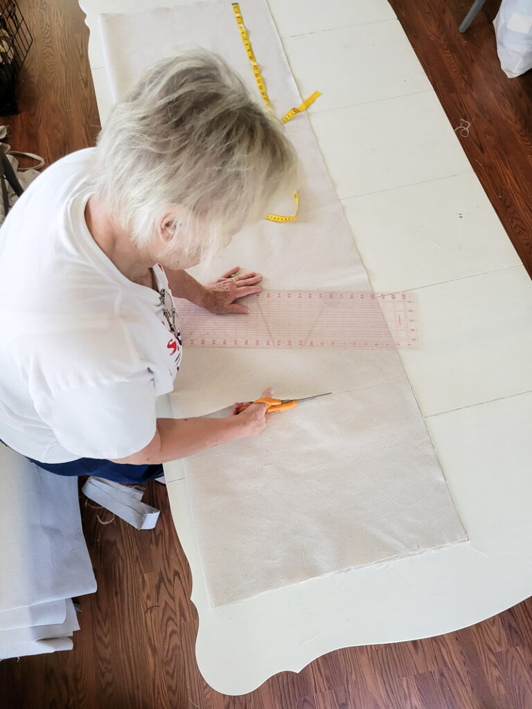 how to make DIY no-sew curtains for a farmhouse feel. This easy no sew curtain idea is perfect for decorating beginners and budget decorating enthusiasts! Drop cloth curtains are cheap and the perfect neutral curtain to accent a room. You can sew up this curtain tutorial but a little fabric glue will do the trick. If you are looking for the perfect white curtains or neutral curtain decor, this is the window valance idea for you! #DIYcurtain #budgetcurtain #nowsewwindowtreatment #nosewcurtain